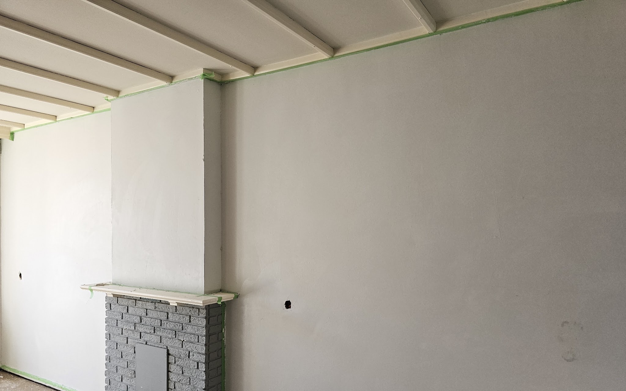 Strak gestuukte wand met schouw en geschilderde balken