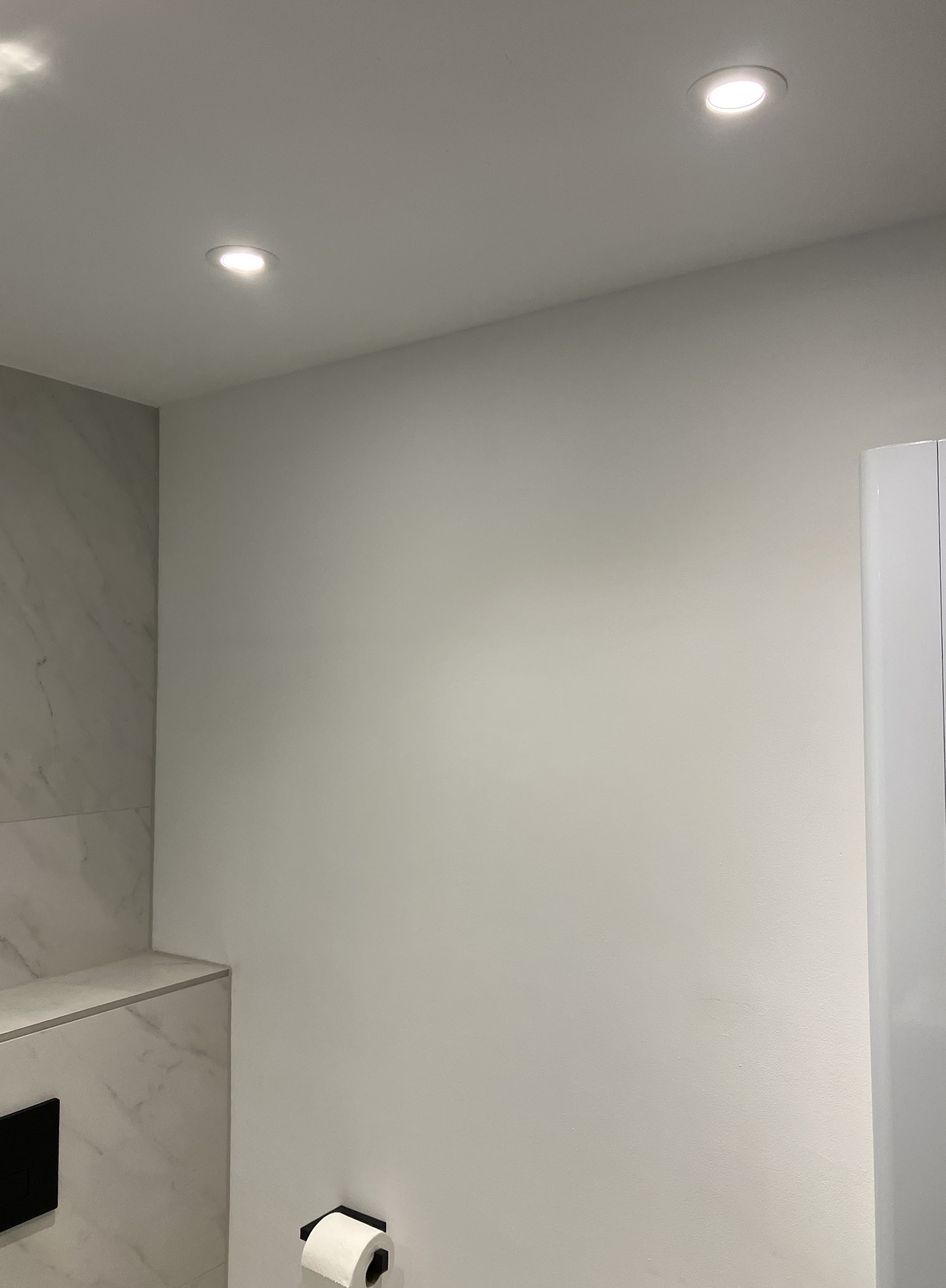 Strak gestuukte badkamerwand met inbouwspots